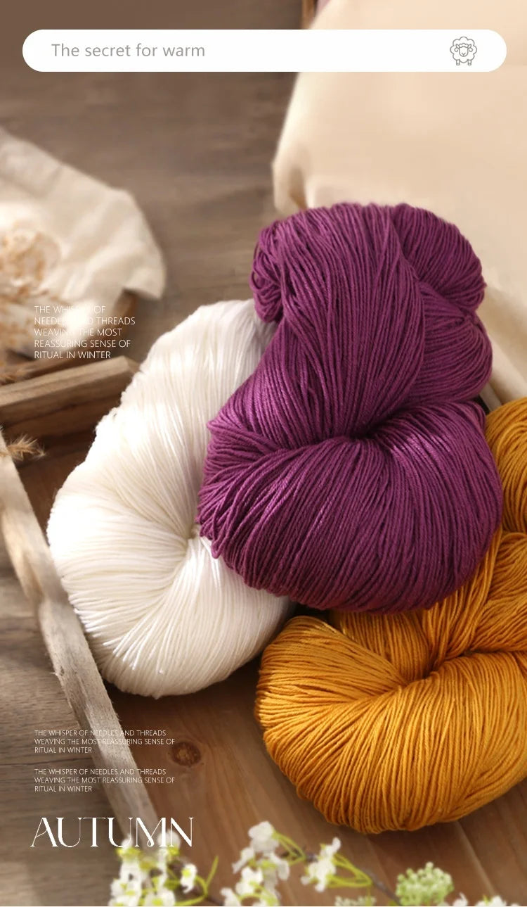 A close-up of purple, white, and orange alpaca blend yarn skeins arranged on a wooden surface.