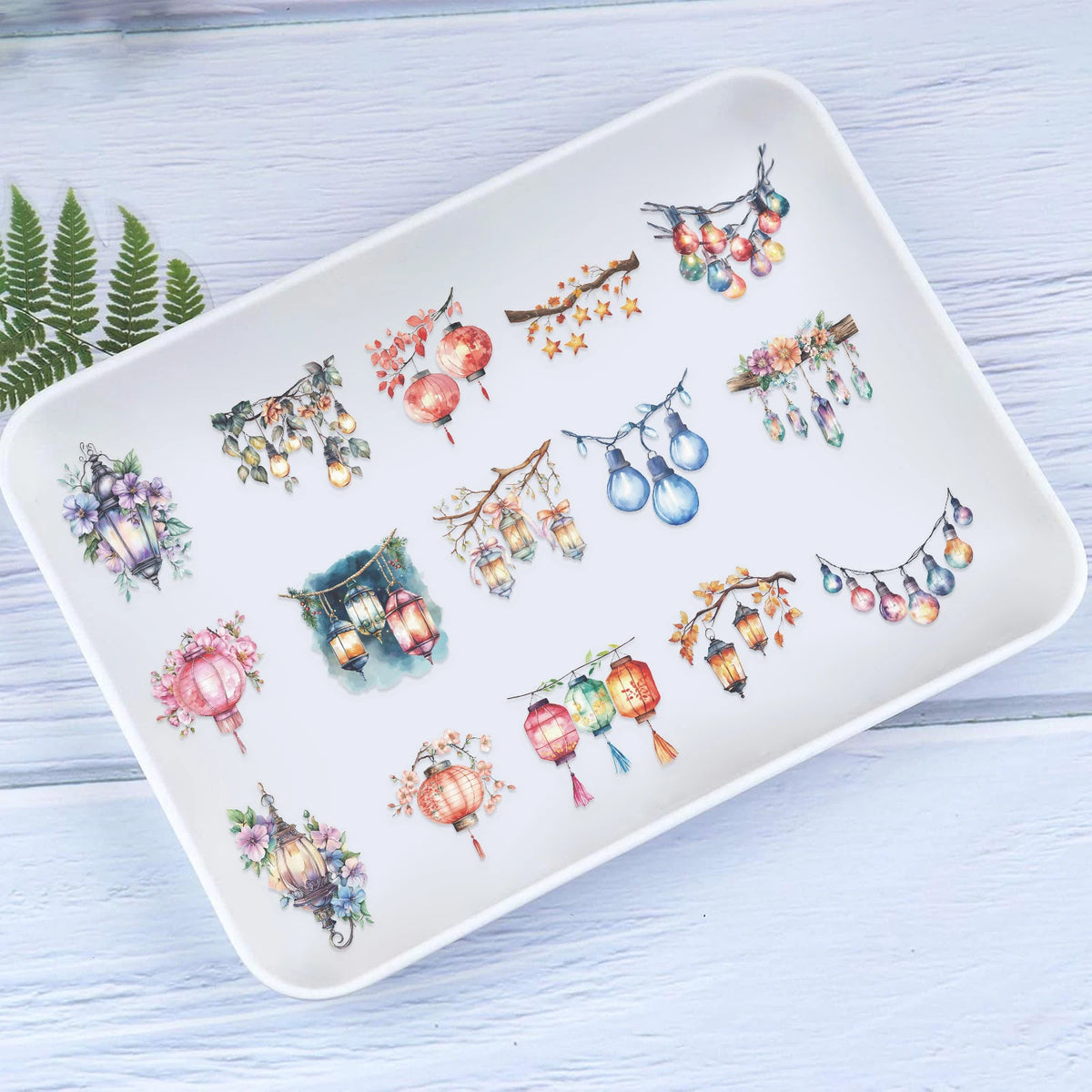 A white ceramic plate features watercolor illustrations of various colorful lanterns and string lights.