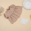 A beige ruffled doll outfit set for a baby doll, including a top and matching underwear.
