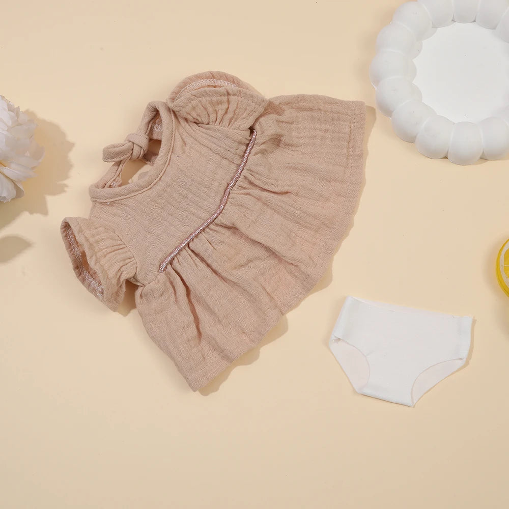 A beige ruffled doll outfit set for a baby doll, including a top and matching underwear.