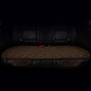 A set of three brown quilted car seat cushions with red accents shown in a dark interior.
