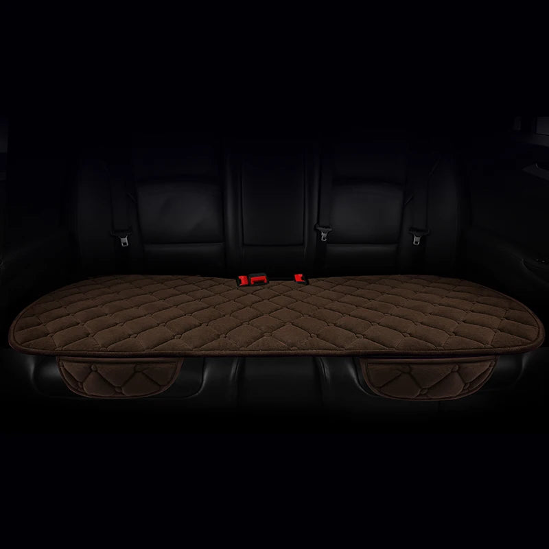 A set of three brown quilted car seat cushions with red accents shown in a dark interior.