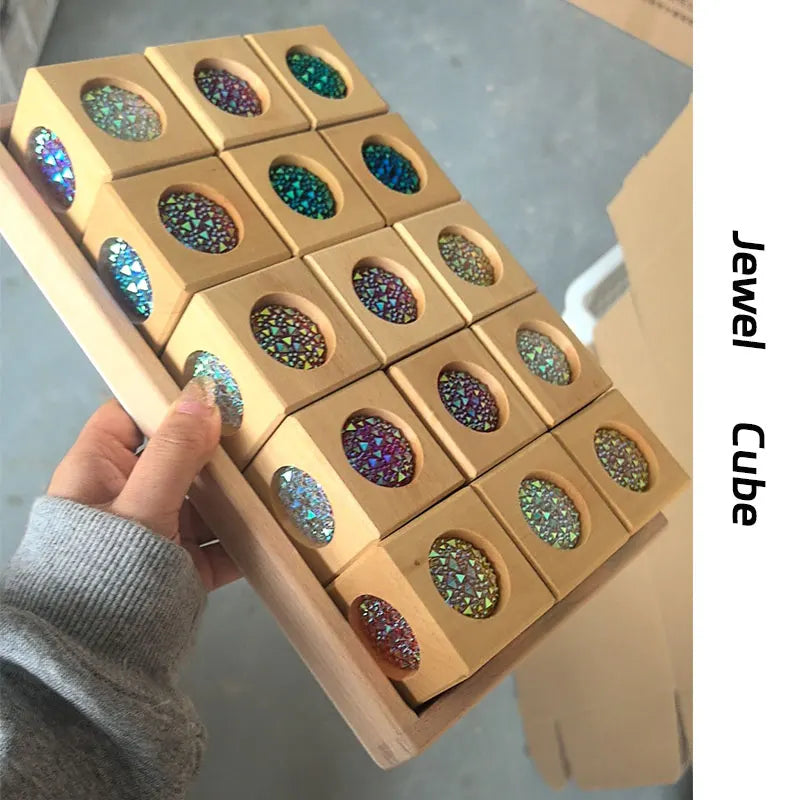 A hand holds a wooden cube puzzle featuring rainbow acrylic building blocks with iridescent colors.