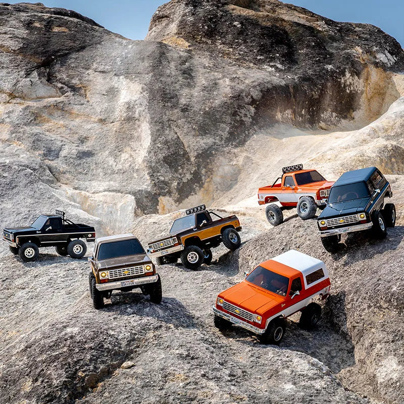 A collection of various scale Chevrolet K5 Blazer RC crawlers parked on rocky terrain.