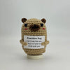 A handwoven crochet pug ornament with brown fur and black eyes, featuring a tag that reads Can't halt the rain but I'm here t