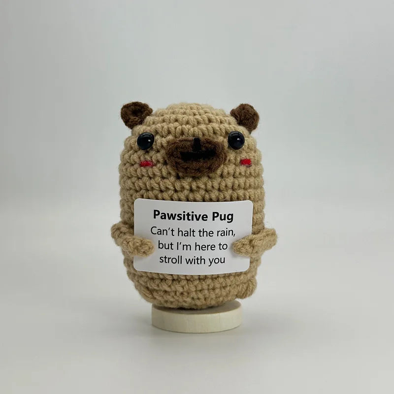 A handwoven crochet pug ornament with brown fur and black eyes, featuring a tag that reads Can't halt the rain but I'm here t
