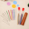 A set of large eye stainless steel sewing needles in various colors arranged next to a wooden storage tube and colorful butto