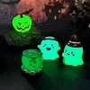 Colección de adornos fantasma y calabaza verdes brillantes sobre una superficie oscura.