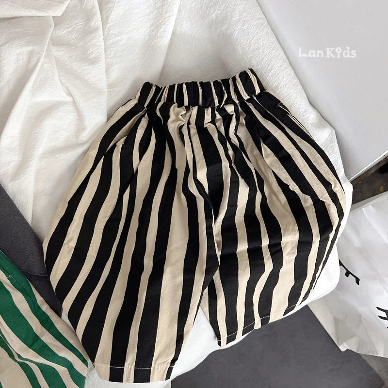 A pair of black and beige vertical striped cotton harem pants for kids lying on a white surface.