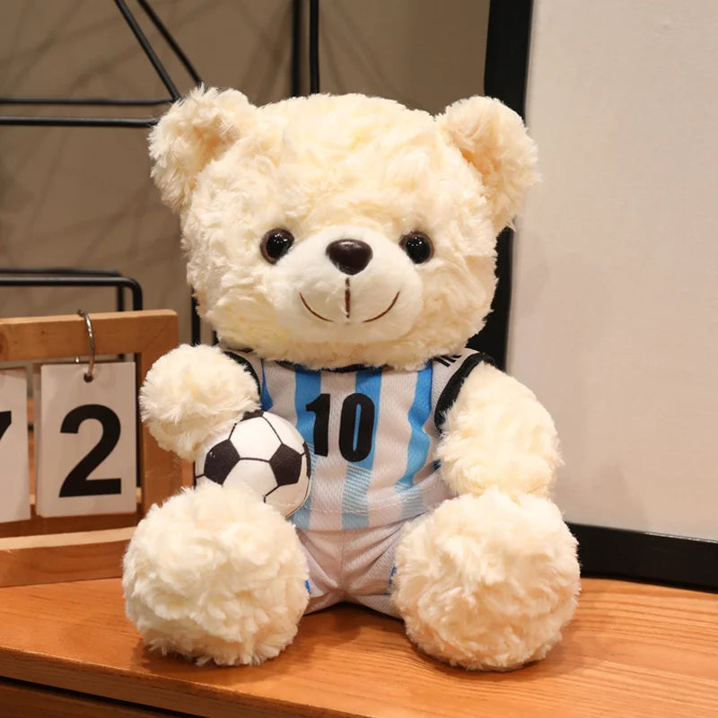 A fluffy cream-colored bear plush toy dressed in a striped football uniform.