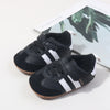 A pair of black and white baby first walkers soft sole shoes are shown resting on a white background.