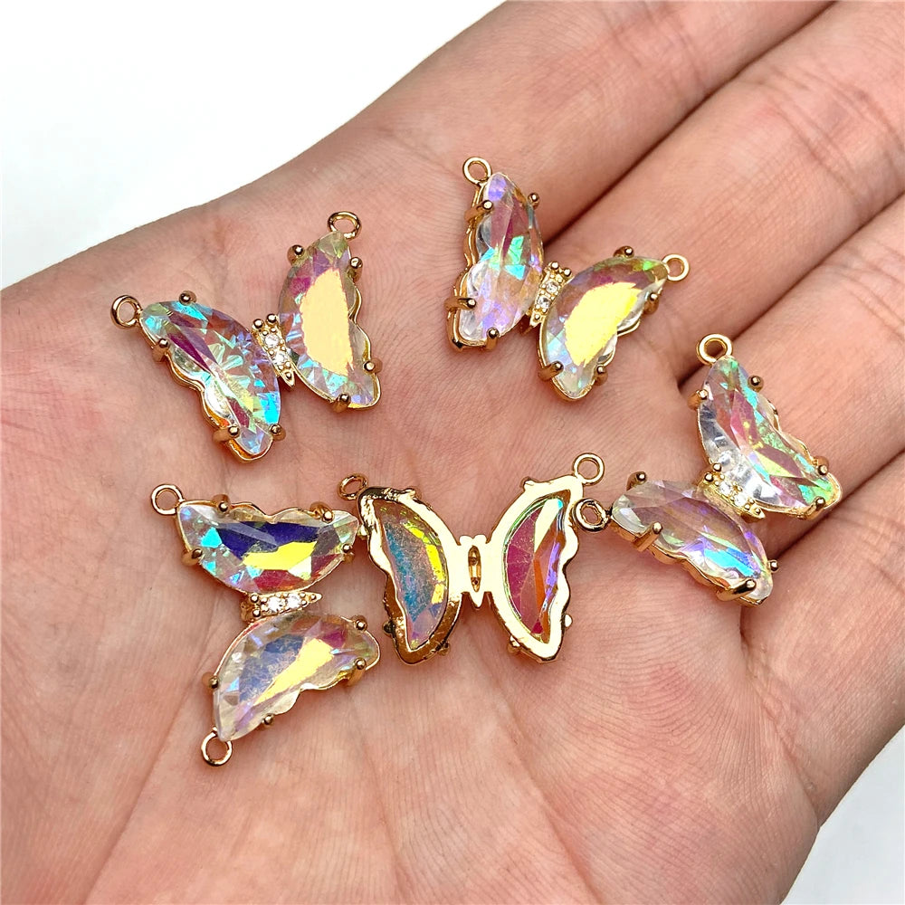 Gold-toned crystal butterfly charm beads displayed on a person's hand.