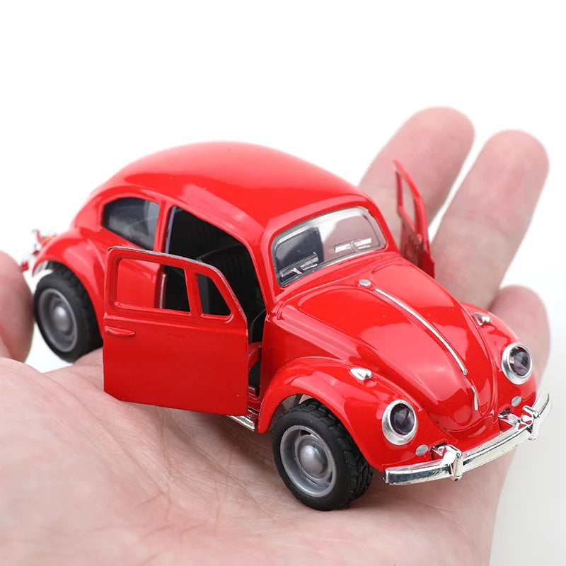 A red 1:38 die-cast model of a classic Beetle car is held in a person's hand.