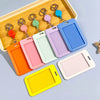 A collection of colorful retractable ID badge holders with keychains arranged in a wooden tray.