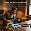 A man plays a guitar in front of a wooden desk with a portable multi-effects processor and cables.