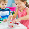 A young girl is making a colorful slime with fingers on a white table.