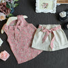 A pink floral chiffon sleeveless top and matching cream shorts set for girls displayed on a dark surface.