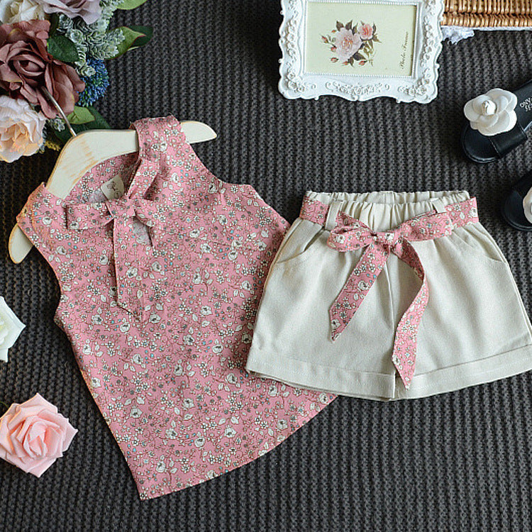 A pink floral chiffon sleeveless top and matching cream shorts set for girls displayed on a dark surface.