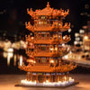 A detailed model of the Yellow Crane Tower built from orange LEGO bricks, illuminated against a dark background.