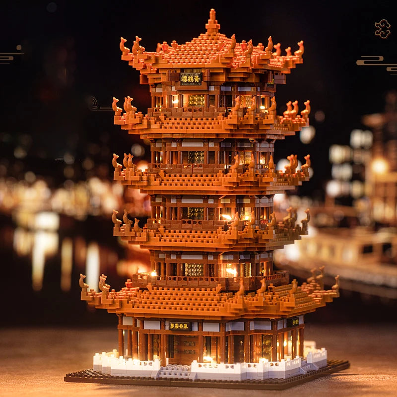 A detailed model of the Yellow Crane Tower built from orange LEGO bricks, illuminated against a dark background.