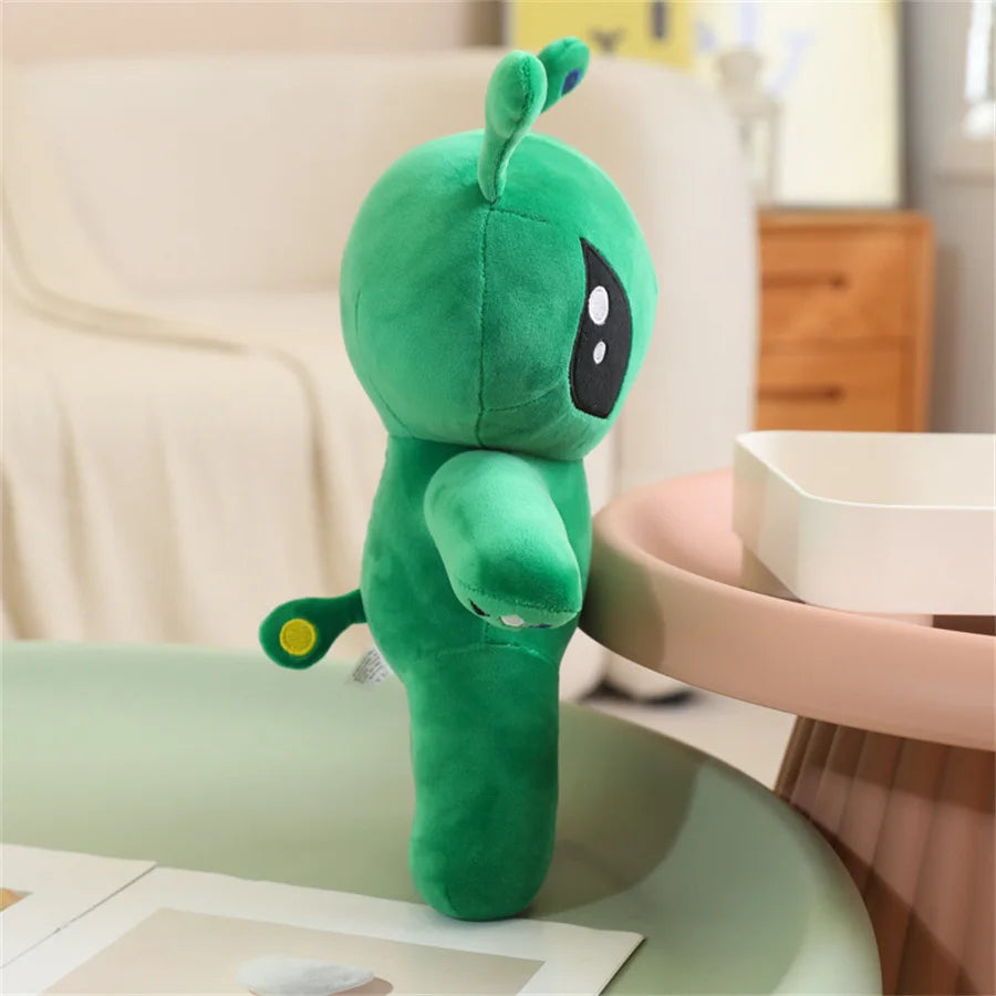 Adorable green alien plush toy with long ears standing on a light green table.