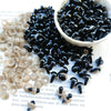 A bowl of small black plastic safety eyes for crafting, alongside a pile of clear eyes.