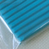 A close-up of a teal polymer clay block with ribbed sides resting on a white surface.