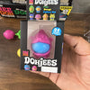 A packaged Nee Doh Jees squishy toy in pink and blue colors is held in a hand.
