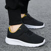 A pair of black and yellow breathable mesh kids' sneakers with hook-and-loop closure resting on a gray surface.