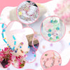 Assortment of mixed color resin beads and stringing materials for jewelry making displayed in various arrangements.