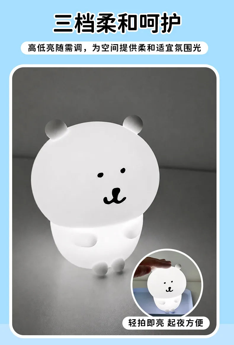 A white silicone lamp shaped like a bear, illuminating a dark background.