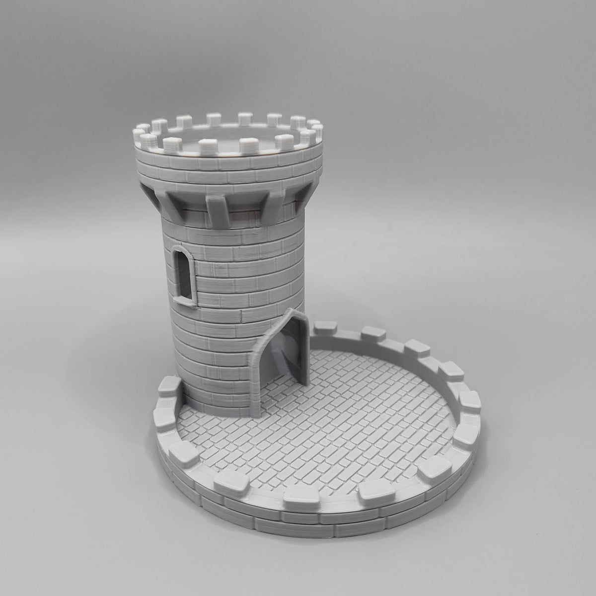 A gray medieval castle dice tower with a tray for tabletop games.