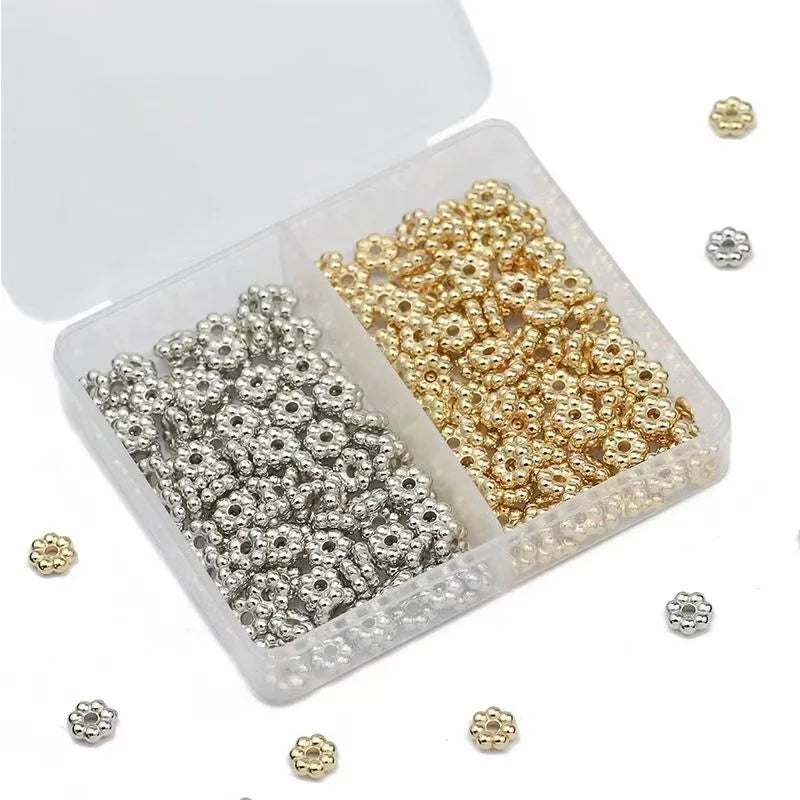 A clear plastic box filled with gold and silver snowflake spacer beads for jewelry making
