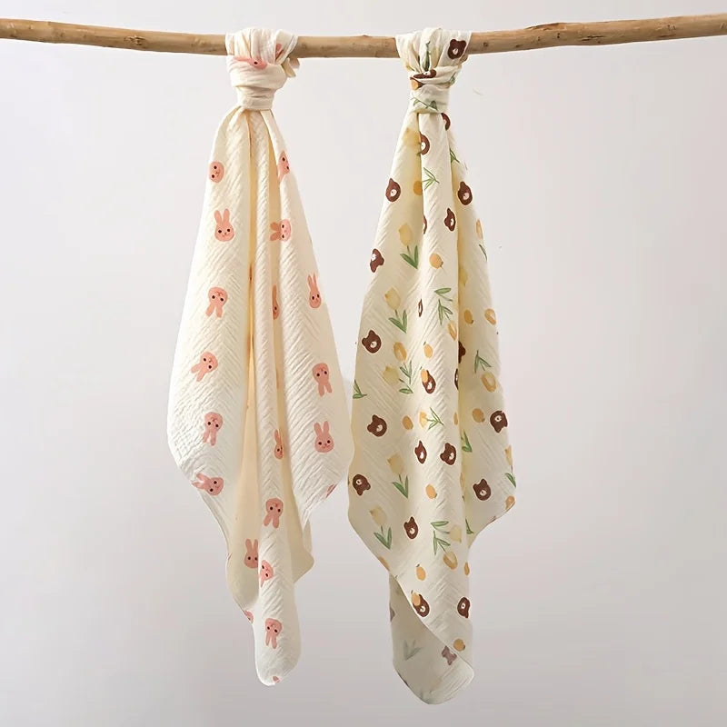 A set of two white baby gauze swaddle blankets tied with fabric, hanging from a wooden stick.