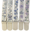 A set of light beige woven guitar straps with floral embroidery and leather accents.