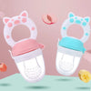 A white silicone baby food feeder with a pink top and a teal base, featuring a ring for teething.