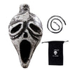 A ceramic Aztec skull whistle with a large open mouth and a coiled black cord.