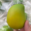A hand holds a bright yellow, smooth stress ball with a squishy texture against a translucent background.