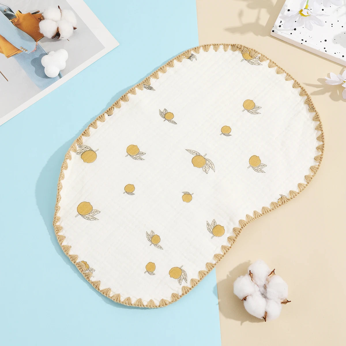 A cream-colored embroidered flat pillow with gold accents rests on a light blue surface.