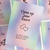 A purple card from a deck titled Open up your heart featuring a line drawing of two hearts.