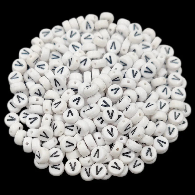 A pile of small white acrylic alphabet letter beads for jewelry making