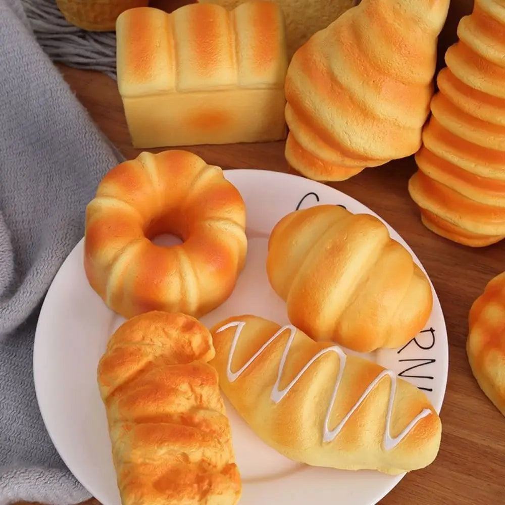 A variety of baked goods including bread, croissants, and donuts are arranged on a wooden surface.