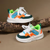 A pair of boys' breathable casual sneakers featuring white, teal, orange, and green accents resting on a brown log.