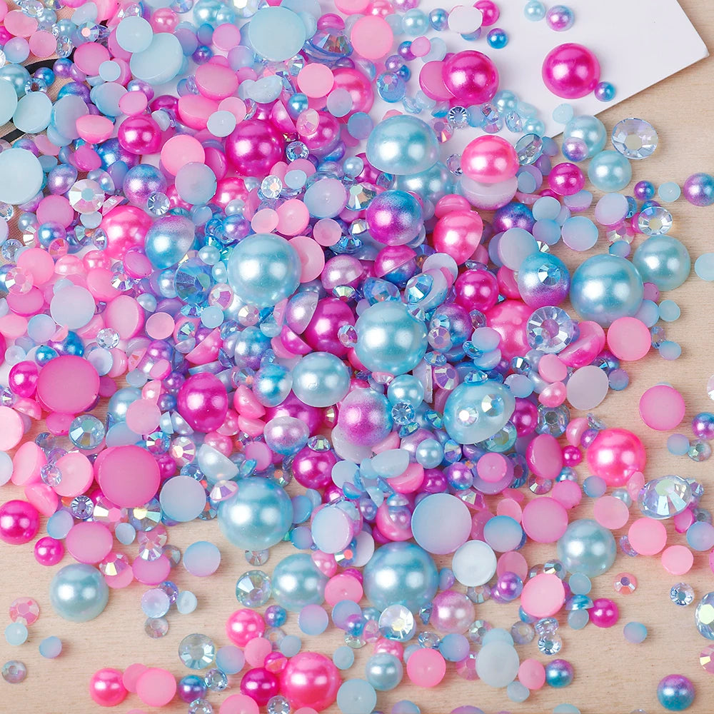 A colorful mix of pink, blue, and purple resin rhinestone pearls with an AB finish scattered on a light wooden surface.
