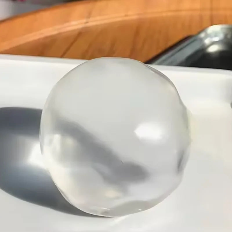 A clear, smooth, spherical fidget ball resting on a white surface.