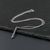 A silver metal saber keychain necklace is laid out on a dark slate surface.