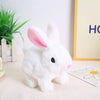 A white rabbit plush toy with pink inner ears sitting on a light surface next to a yellow frame.
