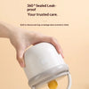 A hand is holding a white insulated breakfast cup with a silicone seal ring.