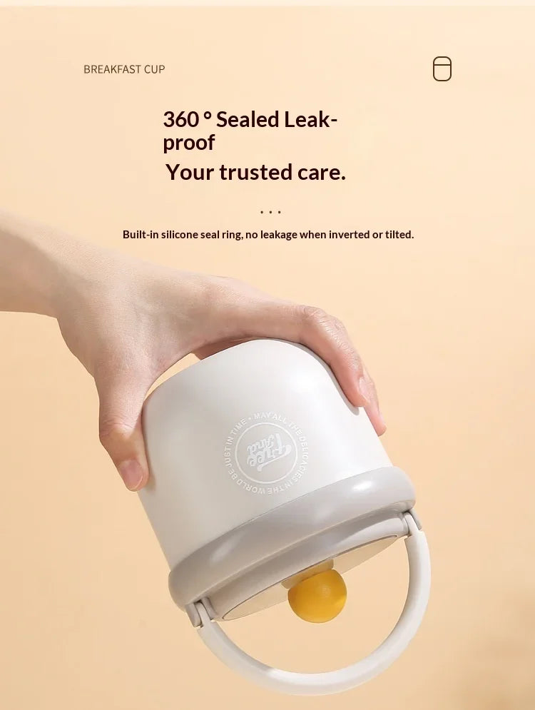 A hand is holding a white insulated breakfast cup with a silicone seal ring.