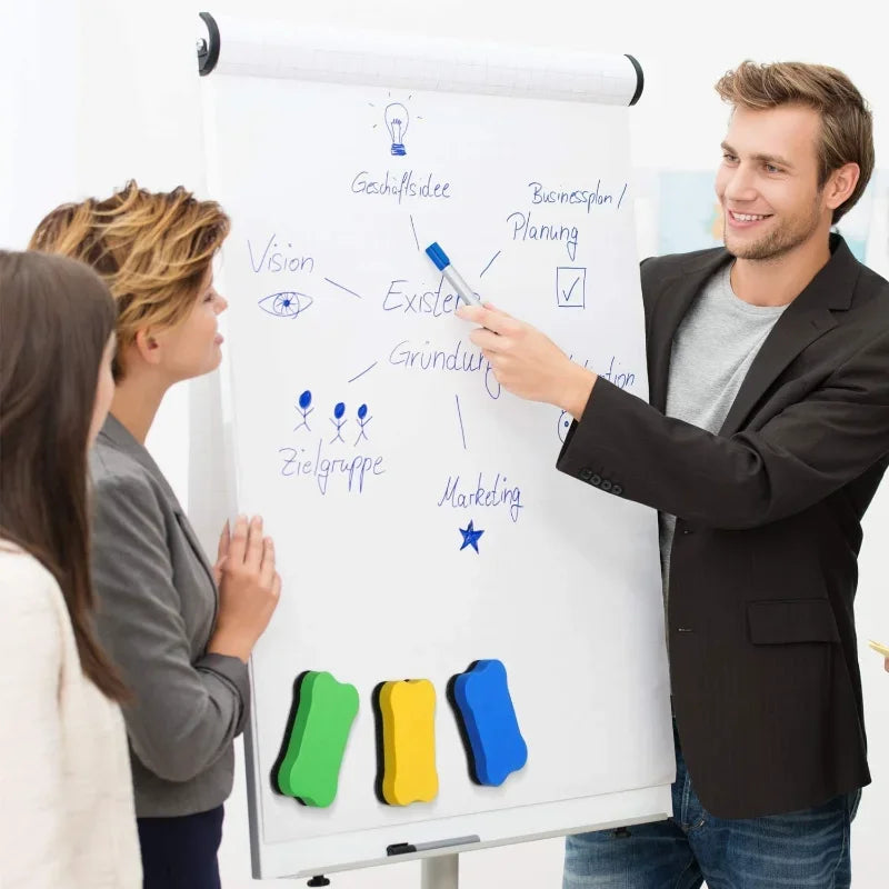 A man points to a whiteboard diagram showing business planning concepts and colored erasers.